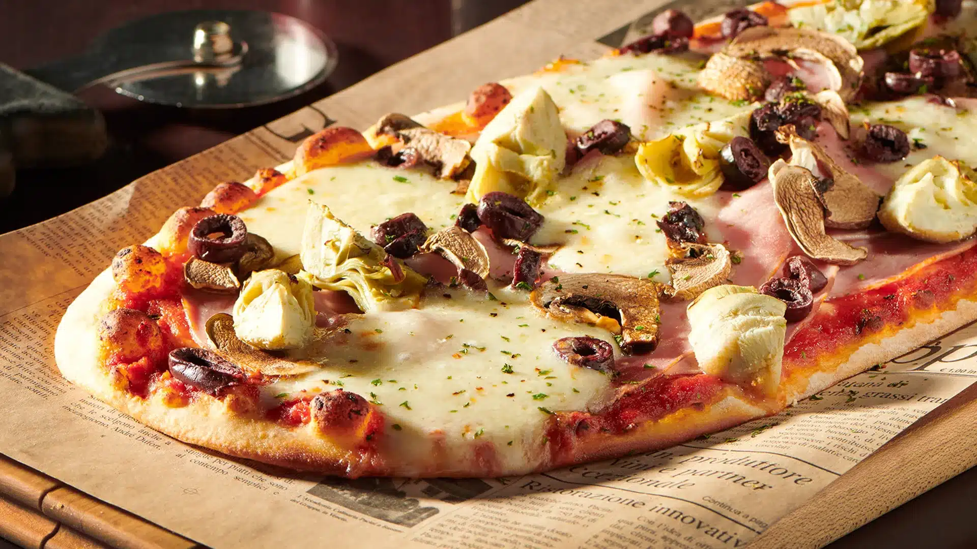 Capricciosa pizza topped with mushrooms, artichokes, ham, and cheese.